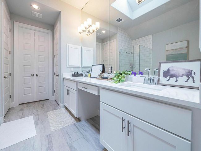 Bathroom featuring double vanity, tiled shower, a skylight, a closet, and a chandelier | Image 15