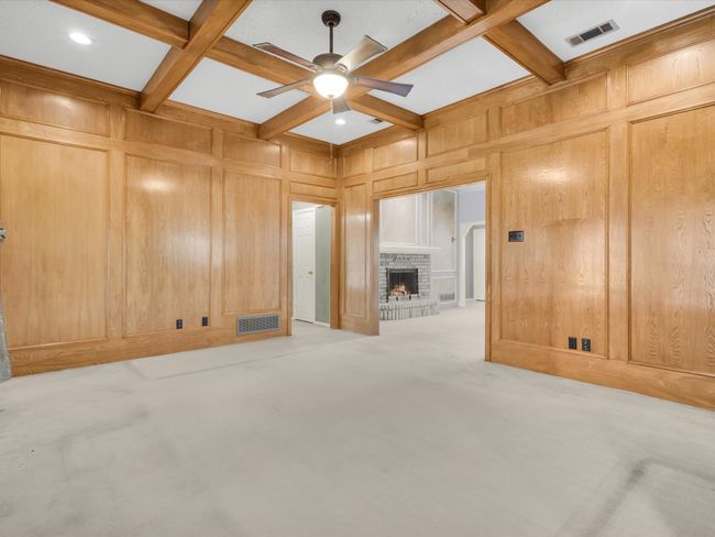 Large cozy den with wood paneling and beamed ceiling. | Image 10