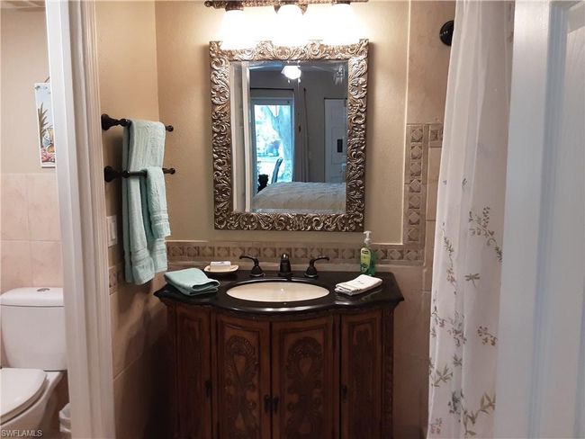 Ensuite bathroom featuring toilet, vanity, tile walls, a wainscoted wall, and ensuite bath | Image 12