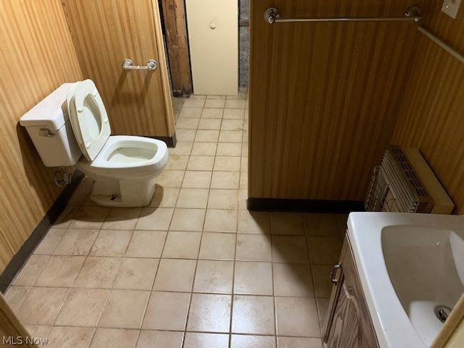 Bathroom with tile floors, toilet, vanity, and wood walls | Image 17