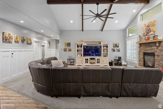 Living area featuring wood finished floors, a stone fireplace, a ceiling fan, beam ceiling, and recessed lighting | Image 5