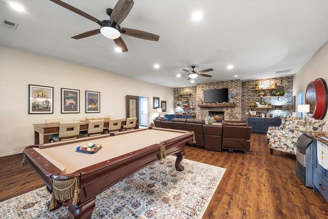 Playroom with ceiling fan, pool table, brick wall, dark wood-type flooring, and a fireplace | Image 32