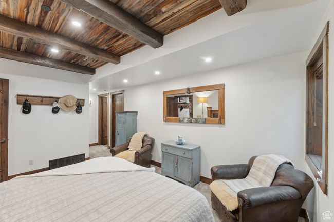 Carpeted bedroom with a wooden ceiling with exposed beams and recessed lighting | Image 42