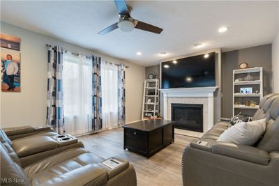 Living room featuring light wood-type flooring, ceiling fan, and a tile fireplace | Image 2