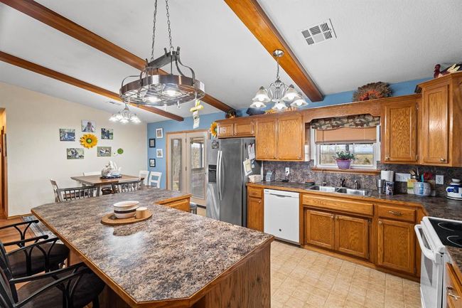 Kitchen featuring visible vents, a chandelier, dark countertops, and white appliances | Image 17