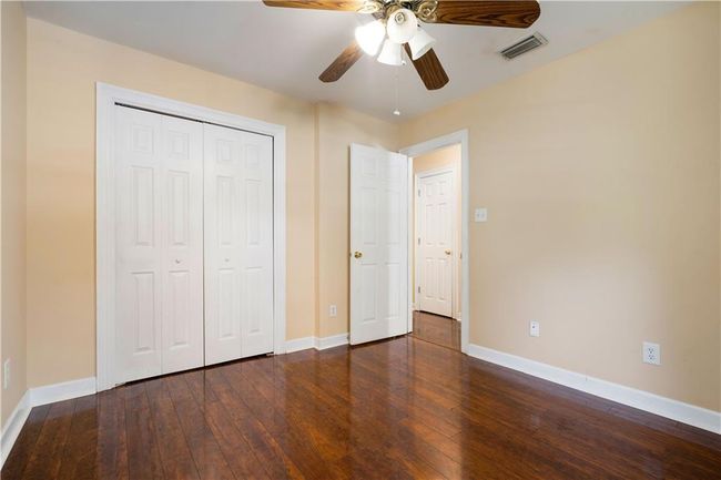Unfurnished bedroom featuring dark wood-style floors, a closet, and a ceiling fan | Image 24