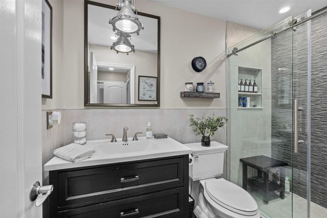 Bathroom with vanity, toilet, a stall shower, and tile walls | Image 14