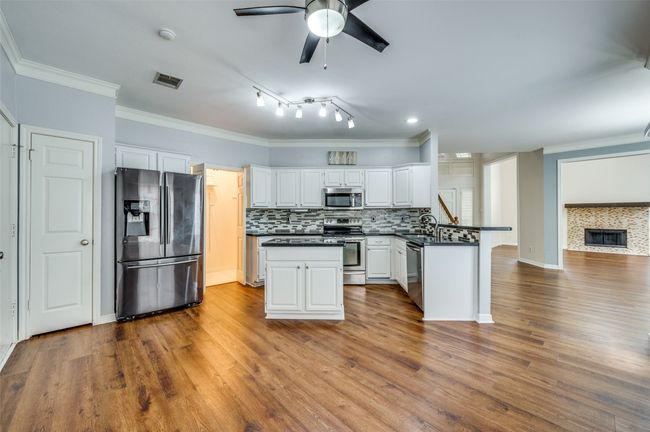 Kitchen featuring appliances with stainless steel finishes, dark countertops, a peninsula, ceiling fan, and ornamental molding | Image 9