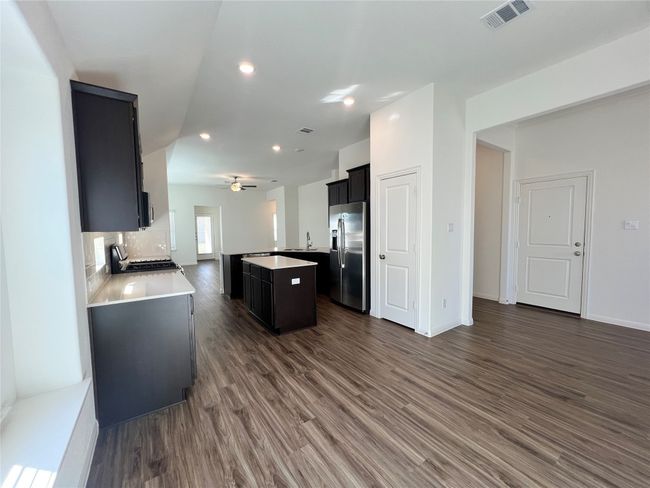 Kitchen featuring open floor plan, dark cabinetry, a kitchen island, dark wood-style flooring, and appliances with stainless steel finishes | Image 9