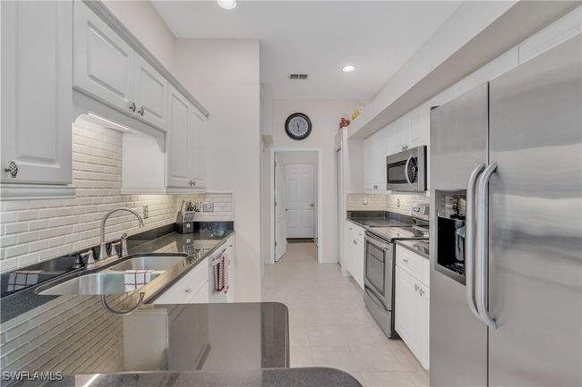 Kitchen with stainless steel appliances, a sink, backsplash, white cabinets, and recessed lighting | Image 12