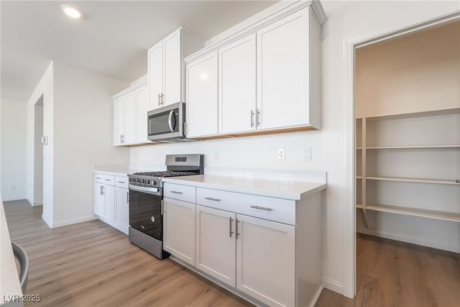 Kitchen with appliances with stainless steel finishes, light wood finished floors, light countertops, and white cabinetry | Image 14