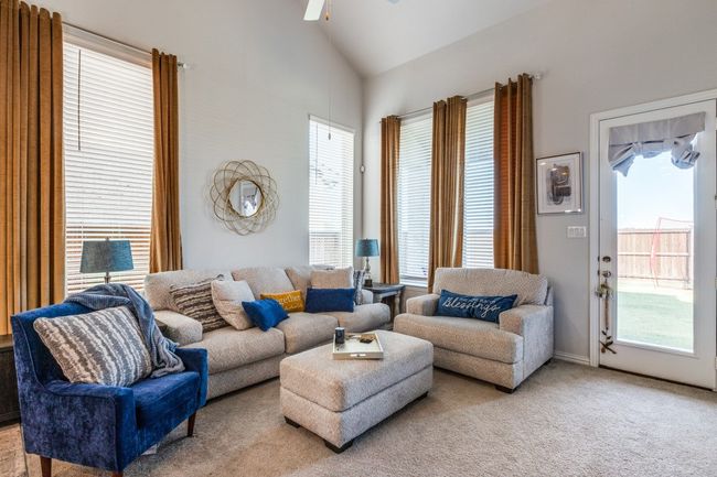 Living area with healthy amount of natural light, a ceiling fan, light carpet, and high vaulted ceiling | Image 9