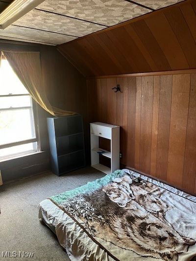 Unfurnished bedroom with lofted ceiling, carpet floors, and wooden walls | Image 3