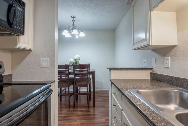 A bright kitchen with a dual sink, range and microwave, emphasizing a practical cooking environment. | Image 15