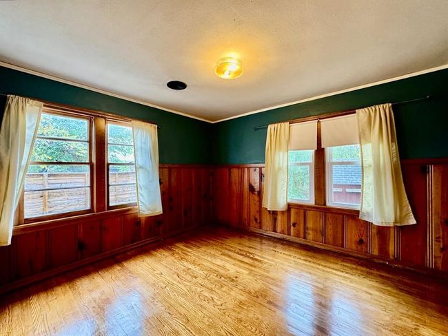 Empty room with wood finished floors, ornamental molding, a wainscoted wall, and wooden walls | Image 14