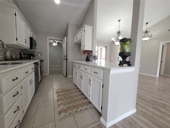 Kitchen with lofted ceiling, a sink, stainless steel appliances, tasteful backsplash, and white cabinetry | Image 11