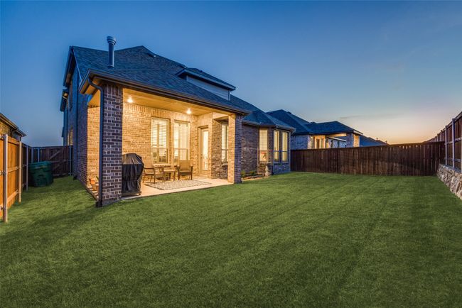 Back of house at dusk featuring a yard, a fenced backyard, brick siding, and a patio | Image 35