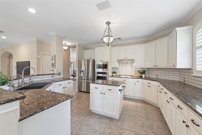 Spacious kitchen with granite countertops, subway tile backsplash, stainless steel appliances, and a center island for extra prep space. | Image 15