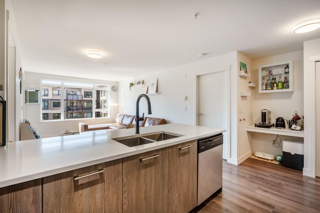 Kitchen featuring dishwasher, light countertops, brown cabinetry, wood finished floors, and modern cabinets | Image 11