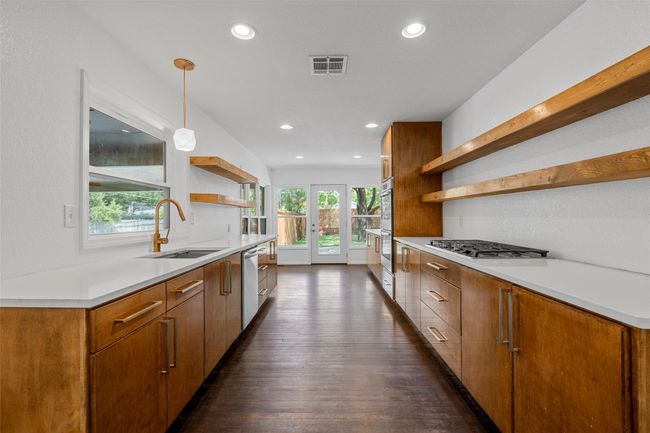Kitchen with open shelves, a sink, stainless steel appliances, dark wood-style floors, and recessed lighting | Image 11