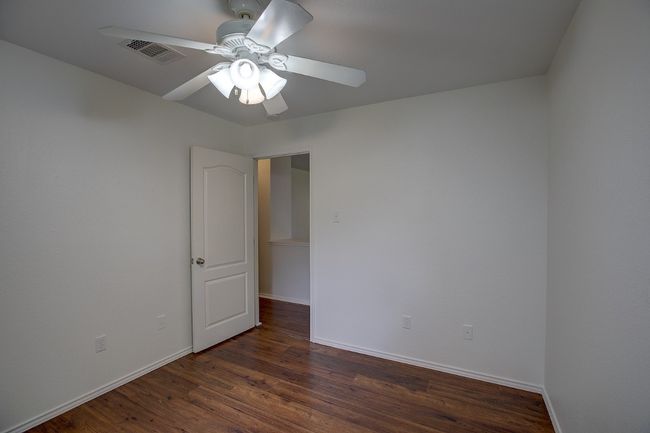 Empty room with ceiling fan, wood finished floors, and baseboards | Image 31