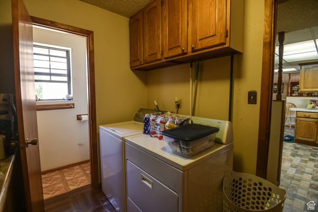 Laundry room featuring washing machine and clothes dryer, cabinet space, and a textured ceiling | Image 26