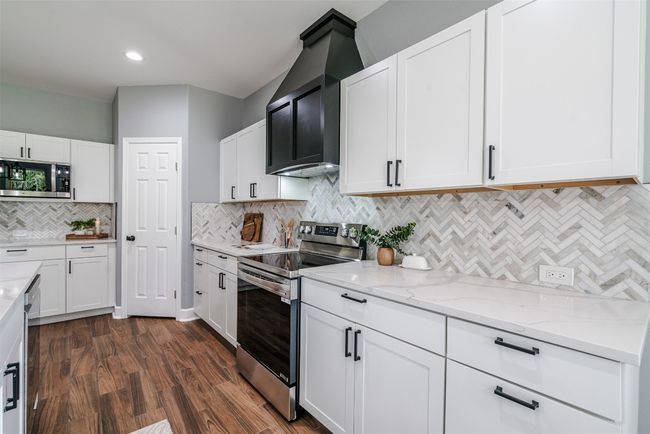 Kitchen featuring appliances with stainless steel finishes, light stone counters, tasteful backsplash, white cabinets, and recessed lighting | Image 8