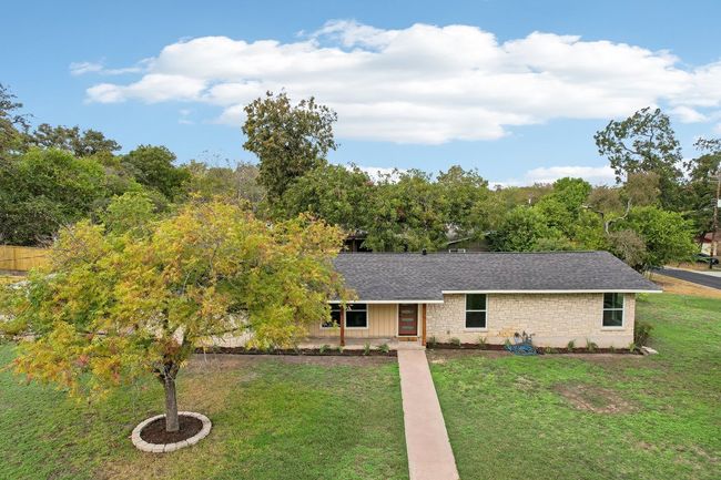 Ranch-style home with a front yard, stone siding, and roof with shingles | Image 23