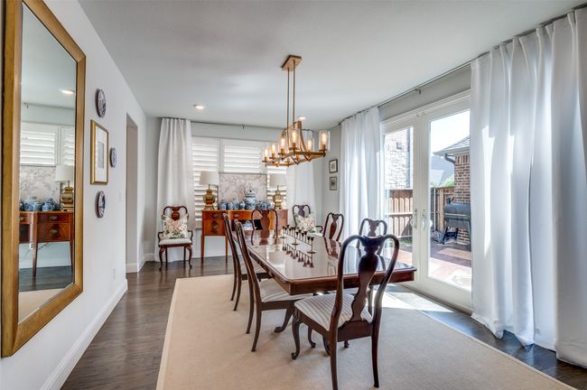 The dining area is filled with natural light, featuring plantation shutters and sliding doors that open to the courtyard—perfect for seamless indoor-outdoor entertaining and easy access to the grill for year-round gatherings. | Image 7