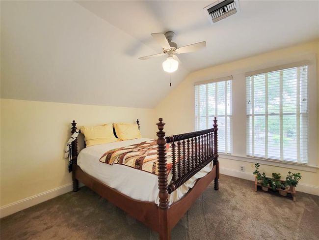 Enjoy stunning views of the lush outdoor grounds from this upstairs bedroom, featuring expansive windows. | Image 24