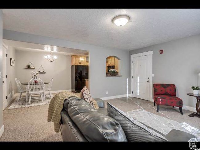 Living area with light carpet, baseboards, a chandelier, and a textured ceiling | Image 5