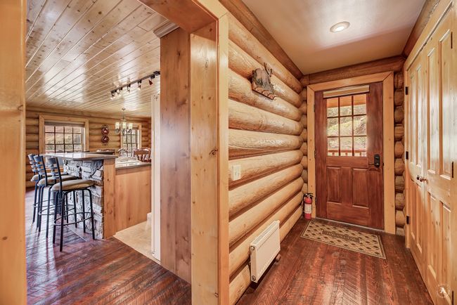 Entryway featuring rustic walls, dark wood-style flooring, and a chandelier | Image 22