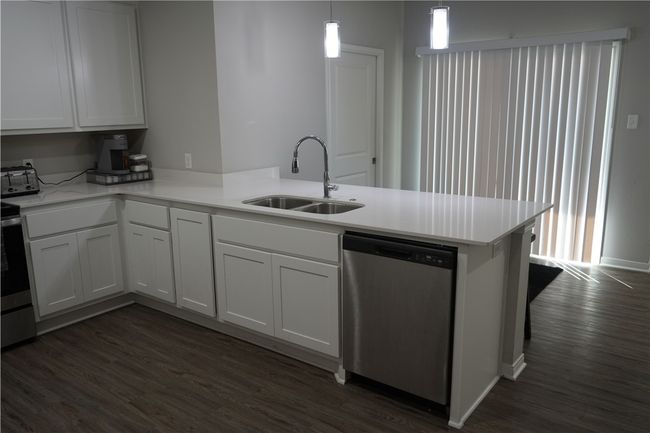 Kitchen featuring a peninsula, appliances with stainless steel finishes, dark wood finished floors, light countertops, and white cabinetry | Image 5