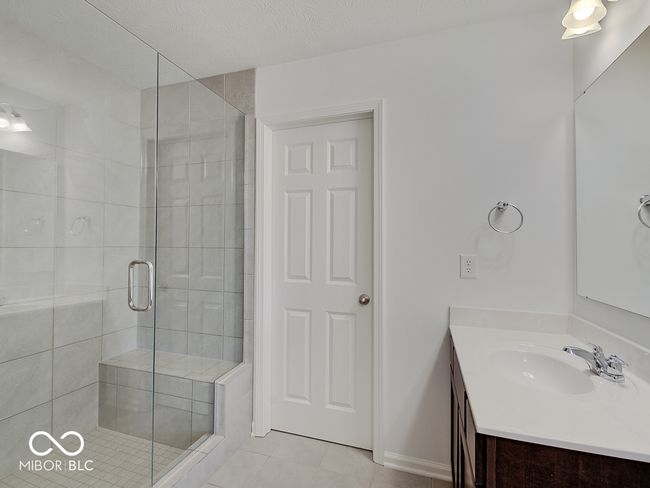 ensuite bathroom featuring full shower, two vanities, ceramic tile floors & 2 walk-in closets | Image 33
