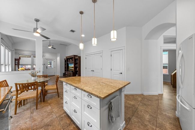 Kitchen with freestanding refrigerator, ceiling fan, arched walkways, a kitchen island, and plenty of natural light | Image 12