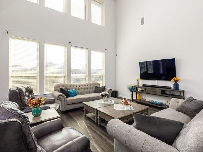 Living room featuring baseboards, visible vents, a high ceiling, and wood finished floors | Image 11