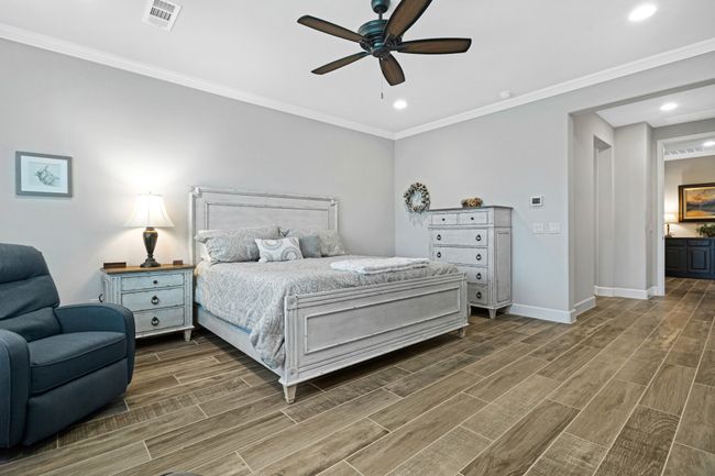 Bedroom featuring wood finish floors, baseboards, crown molding, recessed lighting, and a ceiling fan | Image 25
