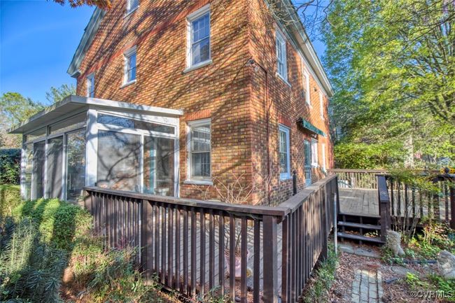 View of side of home with brick siding, a deck, and a sunroom | Image 8