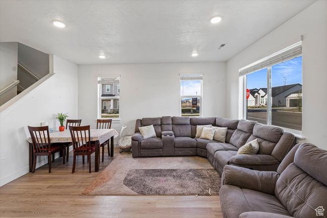Living room with recessed lighting, light wood finished floors, baseboards, and stairs | Image 4