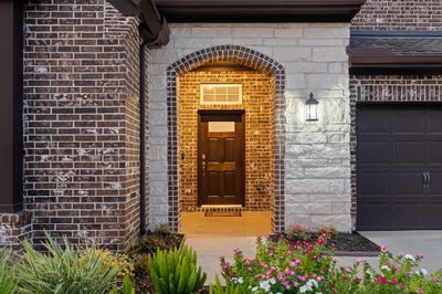 Beautiful landscaping meets you at the epoxy coated front door, covered entrance. | Image 2