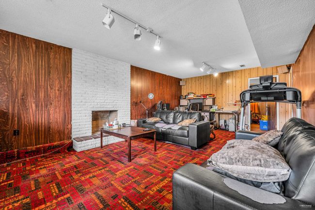 Living area featuring wooden walls, track lighting, a fireplace, a textured ceiling, and carpet flooring | Image 4