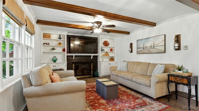 Living area with beamed ceiling, ornamental molding, ceiling fan, a brick fireplace, and built in features | Image 36
