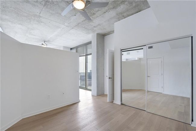 Unfurnished bedroom featuring expansive windows, a ceiling fan, wood finished floors, baseboards, and visible vents | Image 13