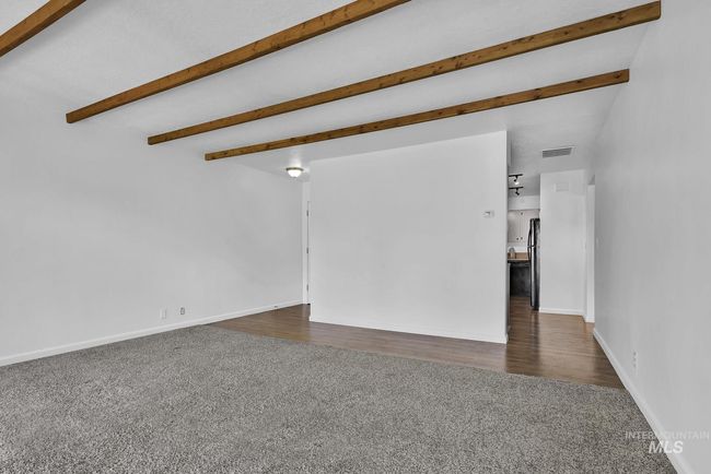 Unfurnished living room with dark colored carpet and beamed ceiling | Image 11