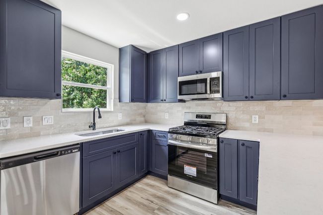 Kitchen featuring appliances with stainless steel finishes, a sink, light countertops, light wood-style floors, and recessed lighting | Image 12