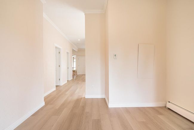Corridor featuring a baseboard heating unit, ornamental molding, and light wood-style floors | Image 10