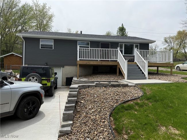 Back of house featuring driveway, a deck, stairway, and a garage | Image 5