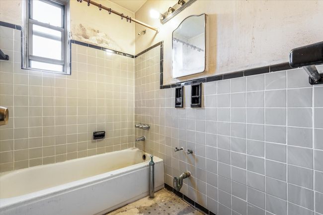 Full bathroom featuring tile walls, shower / bathtub combination, and wainscoting | Image 7