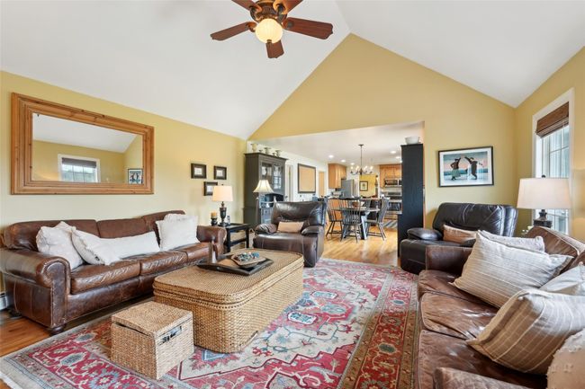 Living area with high vaulted ceiling, light wood-style floors, and ceiling fan with notable chandelier | Image 8