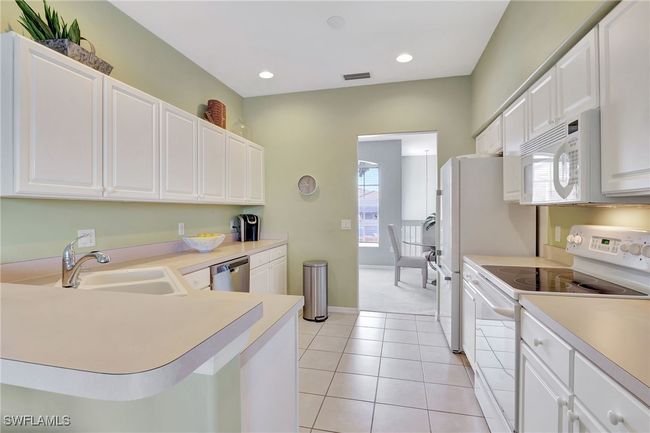 Kitchen with white appliances, a sink, light countertops, white cabinets, and recessed lighting | Image 19